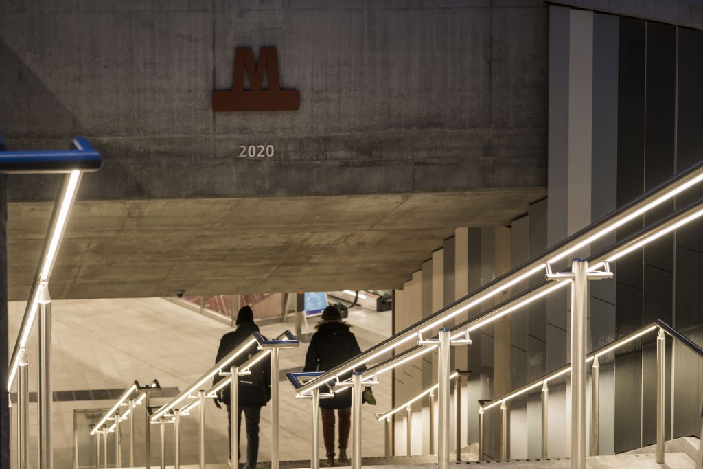 Reizigers vinden goed verlicht hun weg, door de RVS hekwerken met LED verlichting naar de perrons van een metro station in Denemarken.