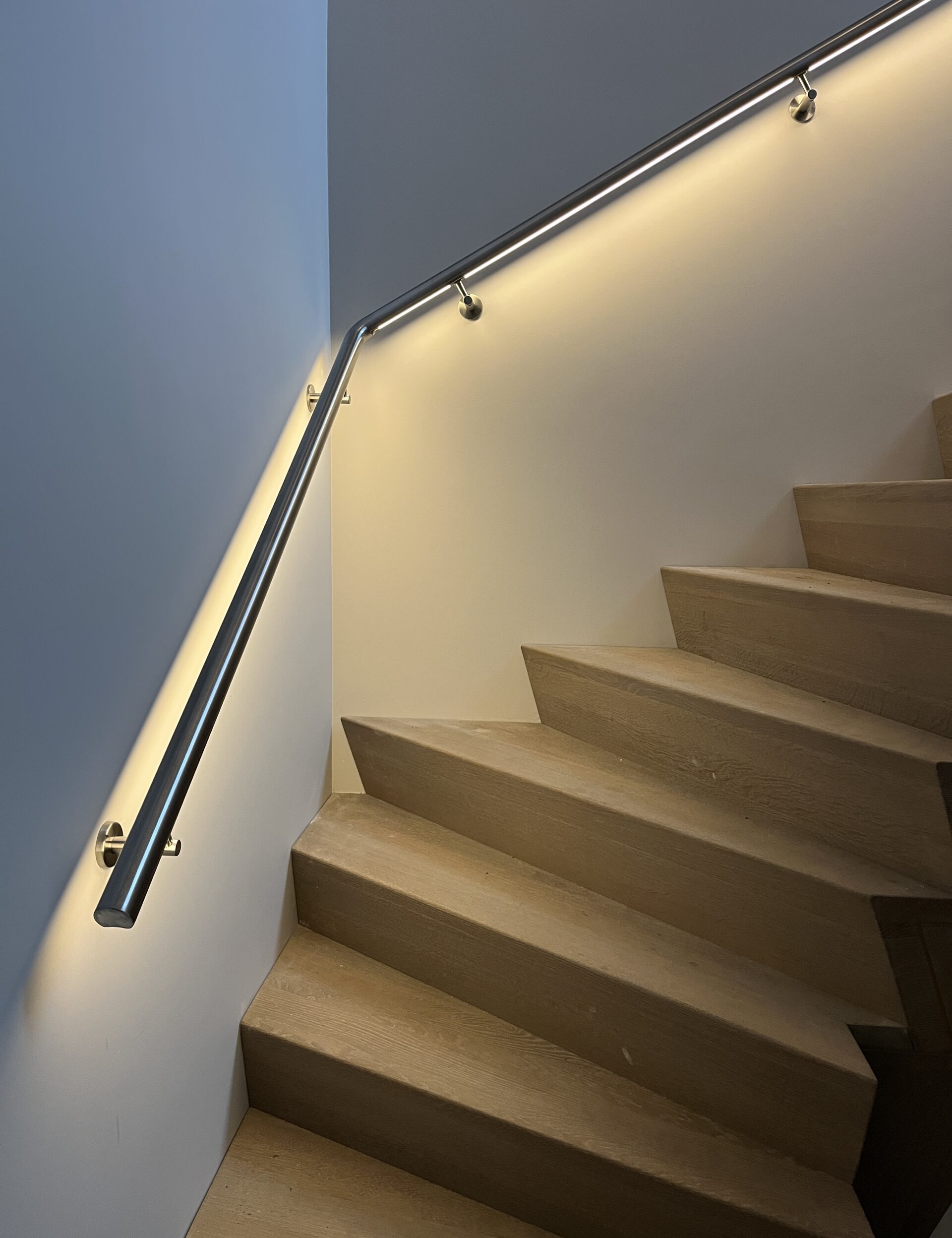Detail van geborstelde RVS trapleuning met geïntegreerde LED‑strip en sensortechniek